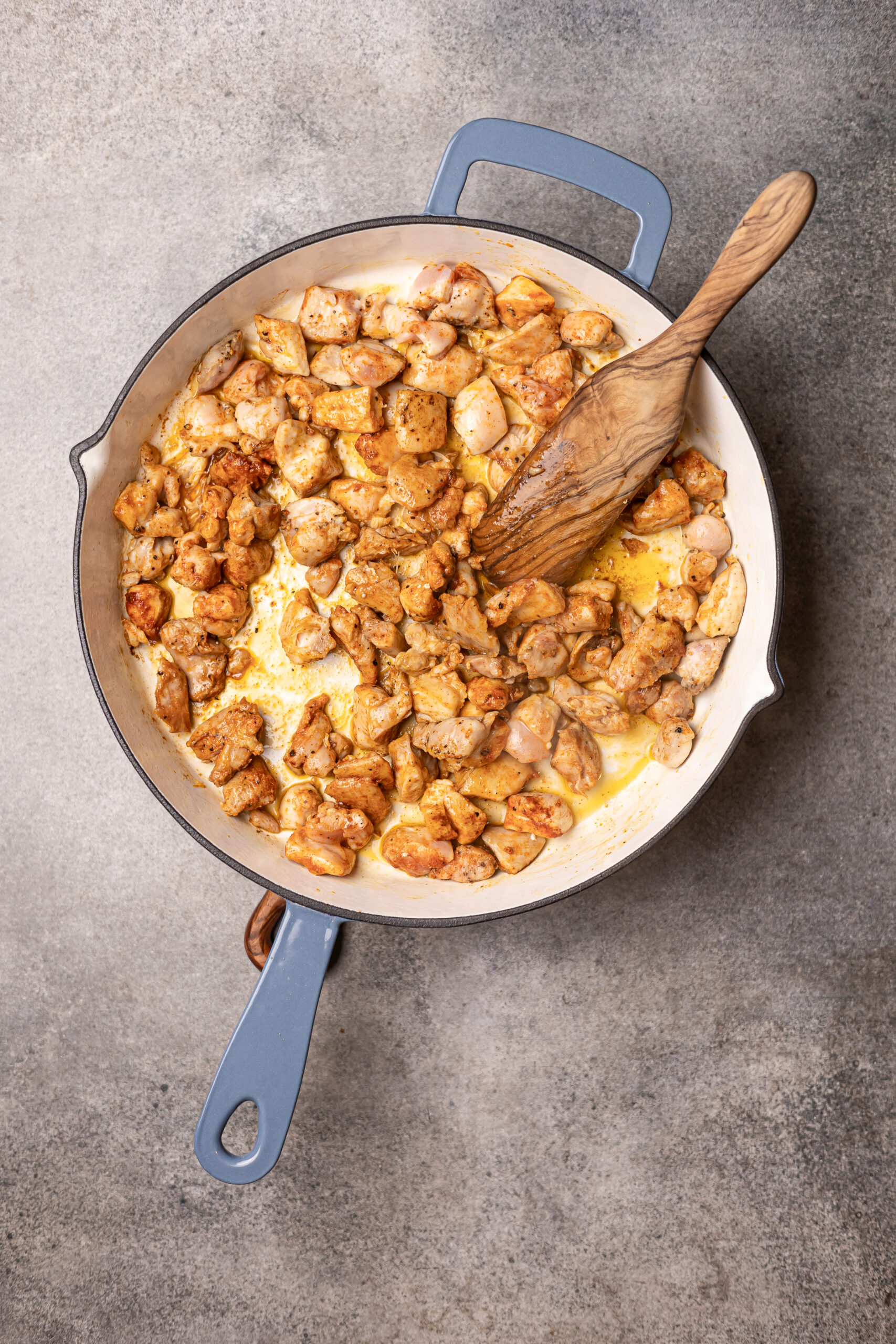 Chicken being cooked in grey skillet for marry me chicken orzo 