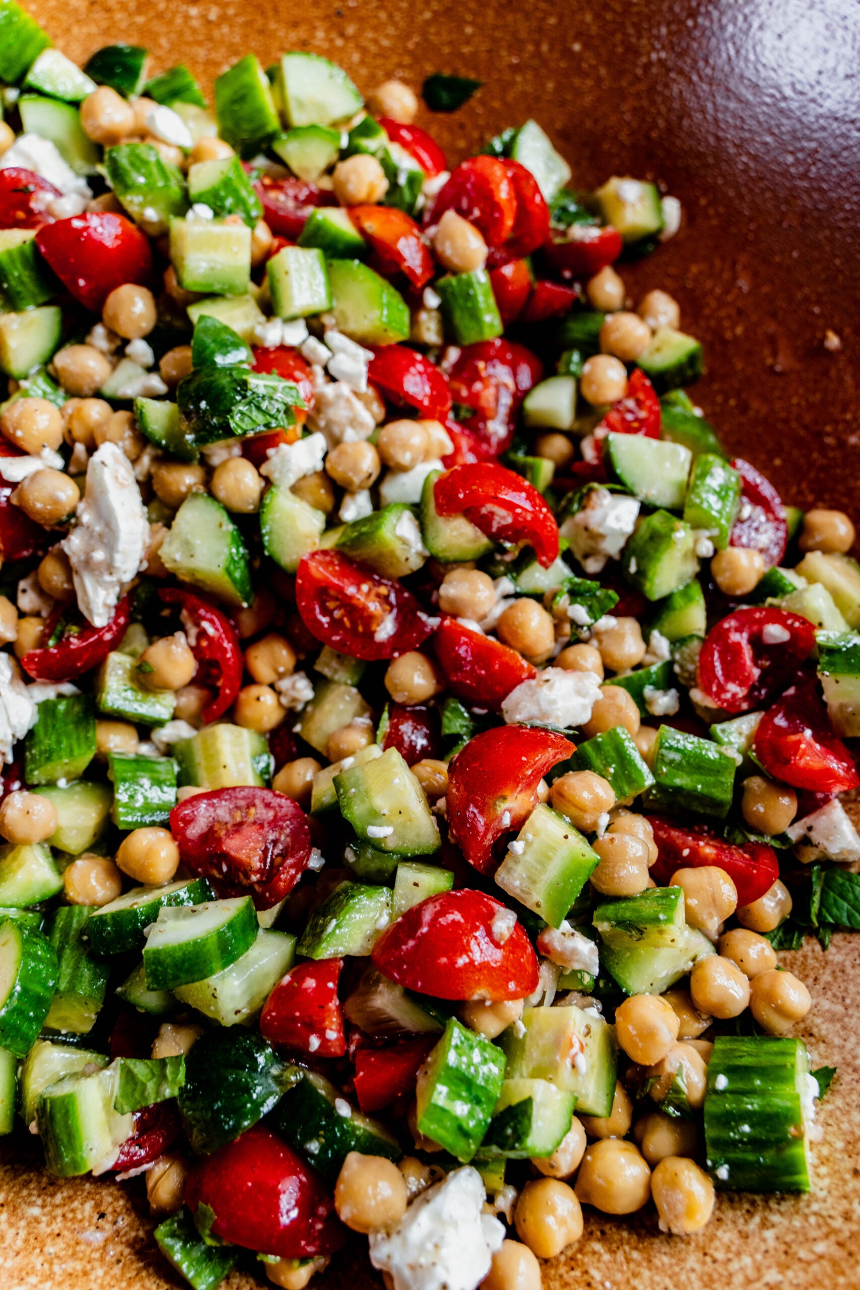 Close-up of a vibrant cucumber, tomato, and feta salad tossed with chickpeas, fresh mint, and a light vinaigrette. The salad features chopped cucumbers, halved cherry tomatoes, crumbled feta cheese, and chickpeas, all coated in a herb-infused dressing and served in a rustic brown bowl.
Ask ChatGPT