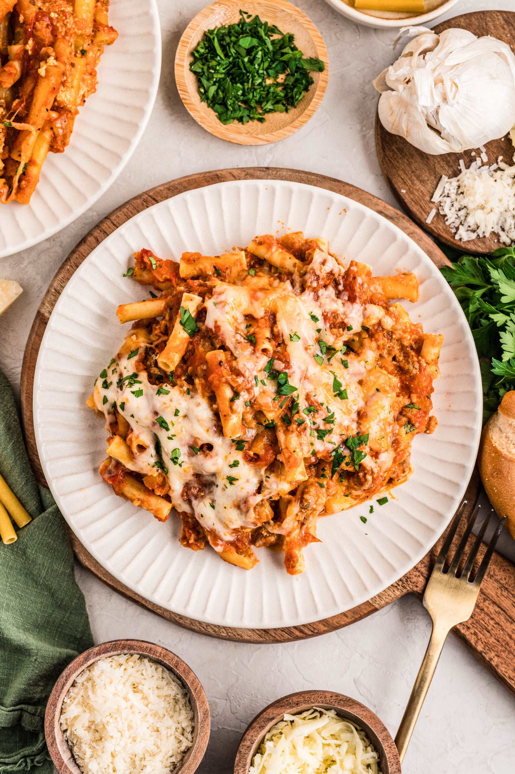 A serving of no boil baked ziti on a white plate, topped with melted mozzarella and sprinkled with fresh