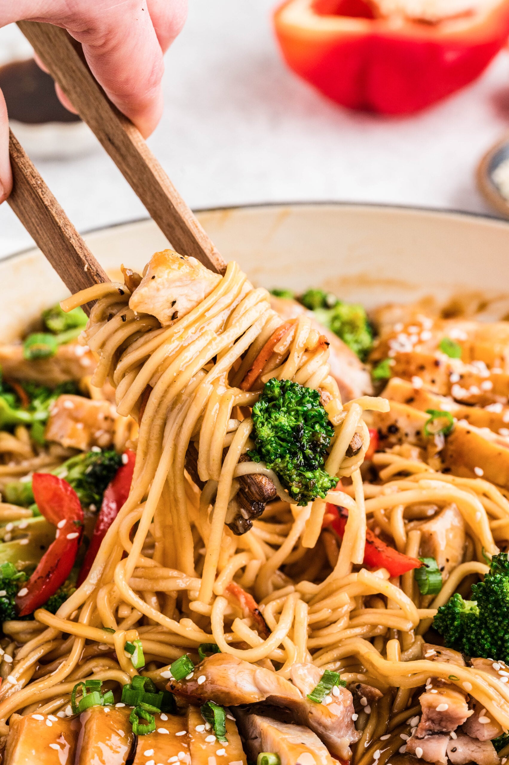 Here is alt text specifically written for SEO and accessibility, featuring **Chicken Teriyaki Bowls**:
**Alt text:**
*A close-up of Chicken Teriyaki Bowls with wooden chopsticks lifting a twirl of saucy lo mein noodles, tender chicken pieces, broccoli florets, and red bell pepper strips from the pan, showcasing the glossy homemade teriyaki sauce and vibrant vegetables.*