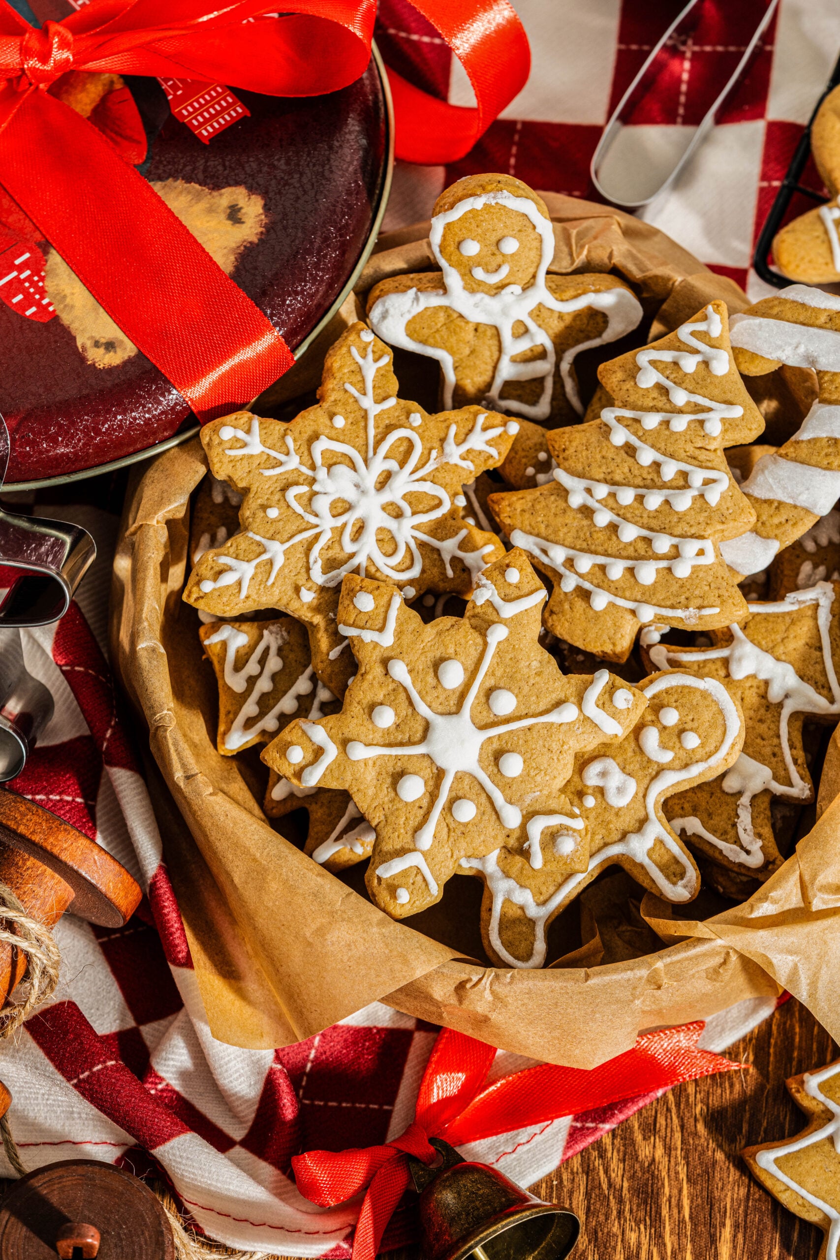 Basket filled with decorated holiday-shaped cookies including snowflakes, gingerbread people, and Christmas trees, showcasing festive frosted gingerbread cookies ready for gifting.